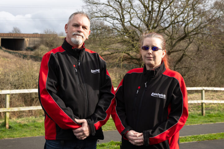 Brian and Nikkie of Austwick Media Ltd, a Cumbria based commercial photography, video production and drone filming company, standing outdoors wearing branded jackets.